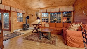L’intérieur d’une cabane en rondins, avec un canapé, une table et une cheminée.