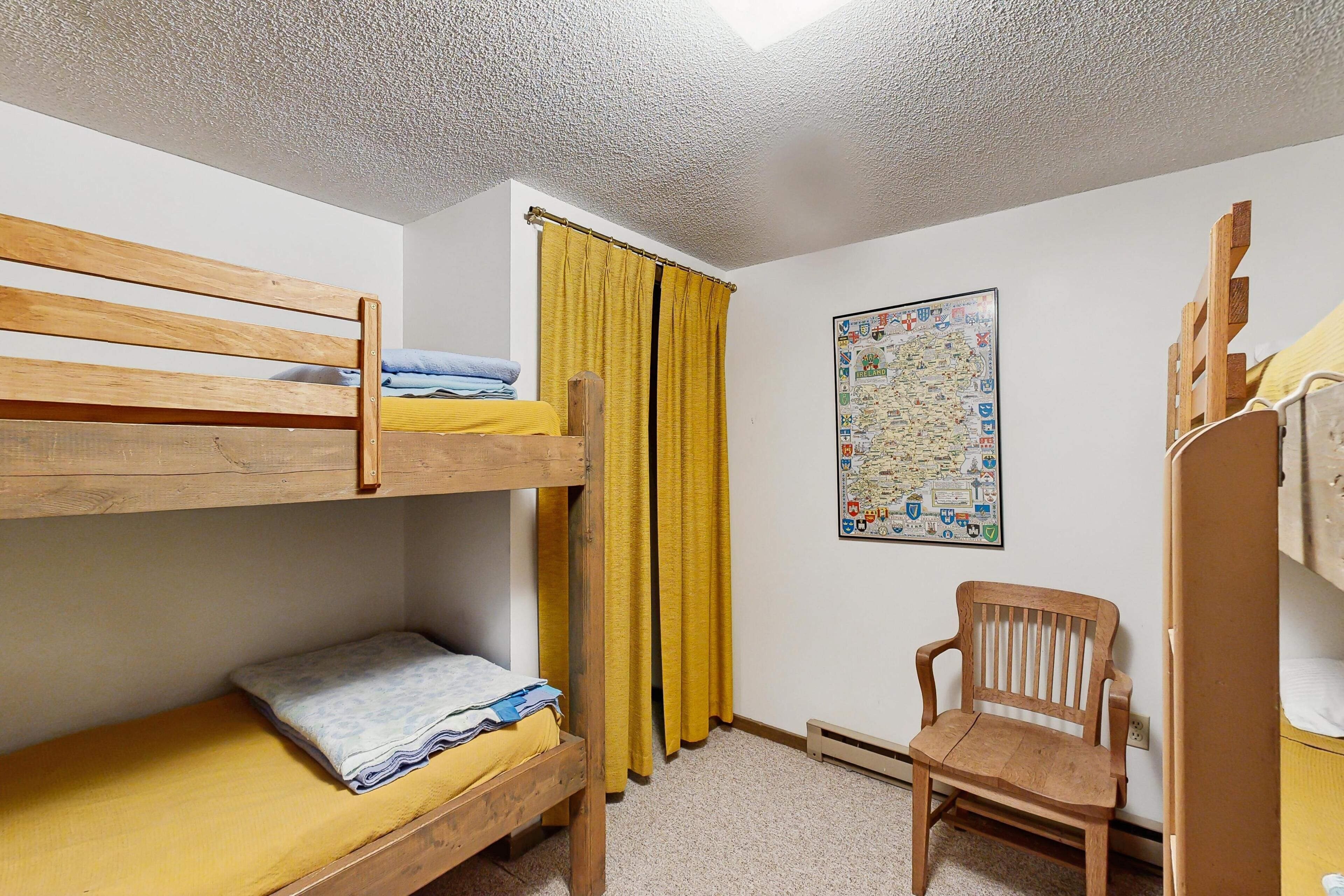 A bunk bed room with a wooden chair and a map on the wall.