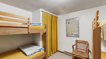 A bunk bed room with a wooden chair and a map on the wall.