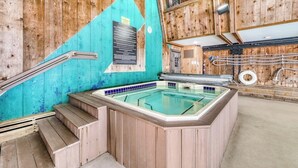 A wooden interior with a hot tub, wooden steps, and a sign on the wall. - Classic Vermont cabin with forest views, pools, hot tub & gym (Wilmington)
