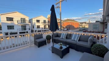 An outdoor balcony with a sofa, a table, and string lights.
