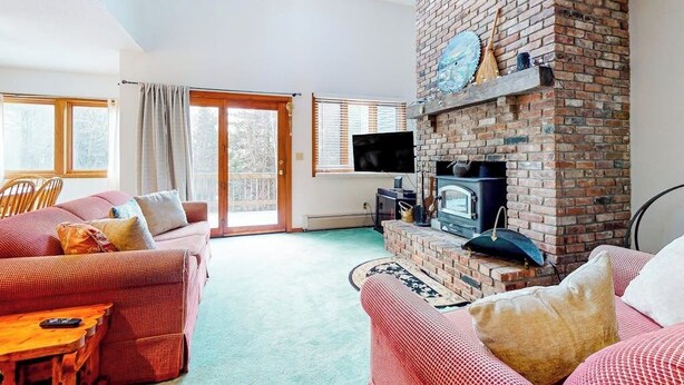 A living room with a brick fireplace, a sofa, a television, and a large window.