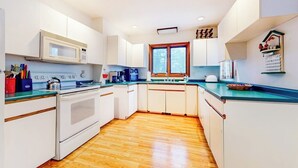 A compact kitchen with white cabinets, a microwave, a stove, and a window.