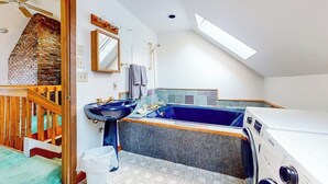 A bathroom with a bathtub, a sink, a mirror, and a ceiling fan.
