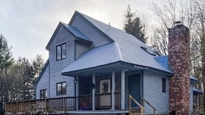 A two-story house with a porch, a chimney, and a deck.