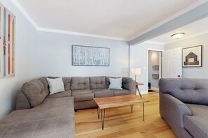 A living room with a sectional sofa, a wooden coffee table, and a grey armchair.