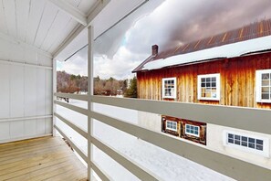Eine Holzterrasse mit Blick auf ein rustikales Gebäude mit zahlreichen Fenstern und einem Metalldach.