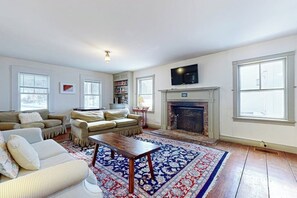 Ein Wohnzimmer mit Kamin, Sofas, einem Couchtisch und einem Fernseher.