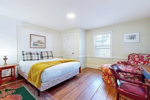 Ein Schlafzimmer mit Bett, Nachttisch, Stuhl, Fenster und Tür.