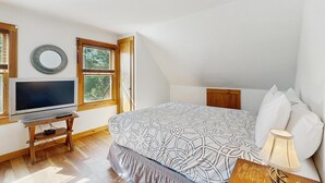 Quarto com cama, televisão, janela e abajur.