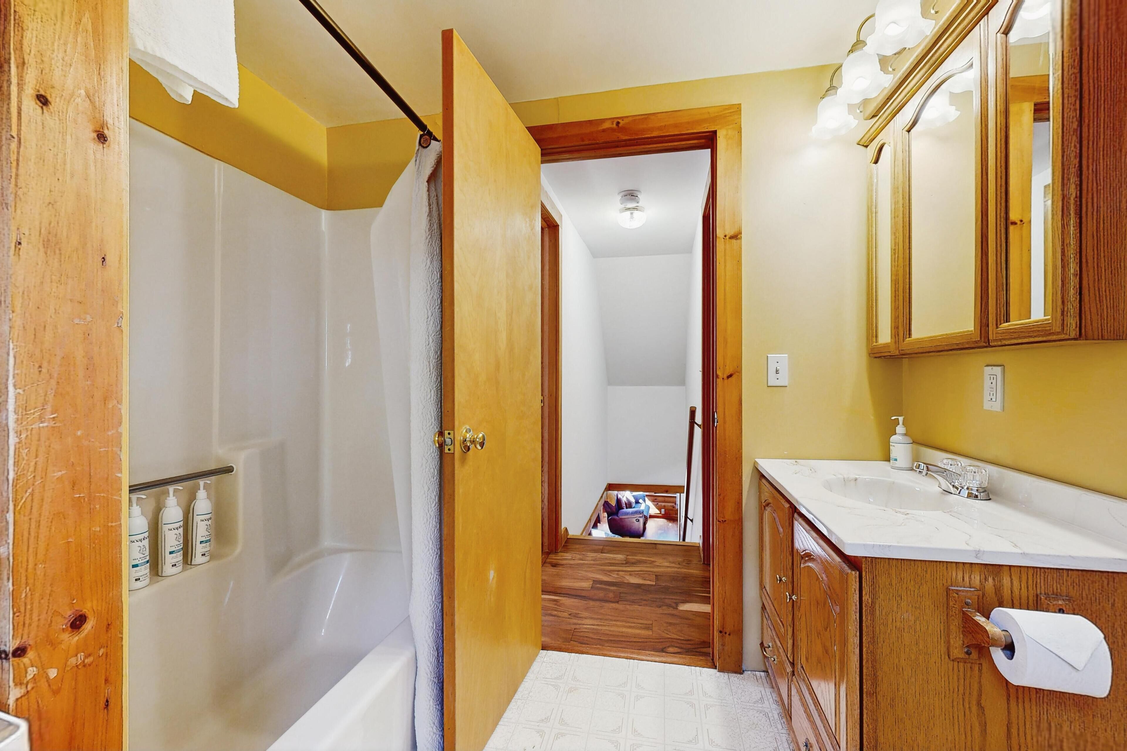 A bathroom with a bathtub, a sink, and a mirror.