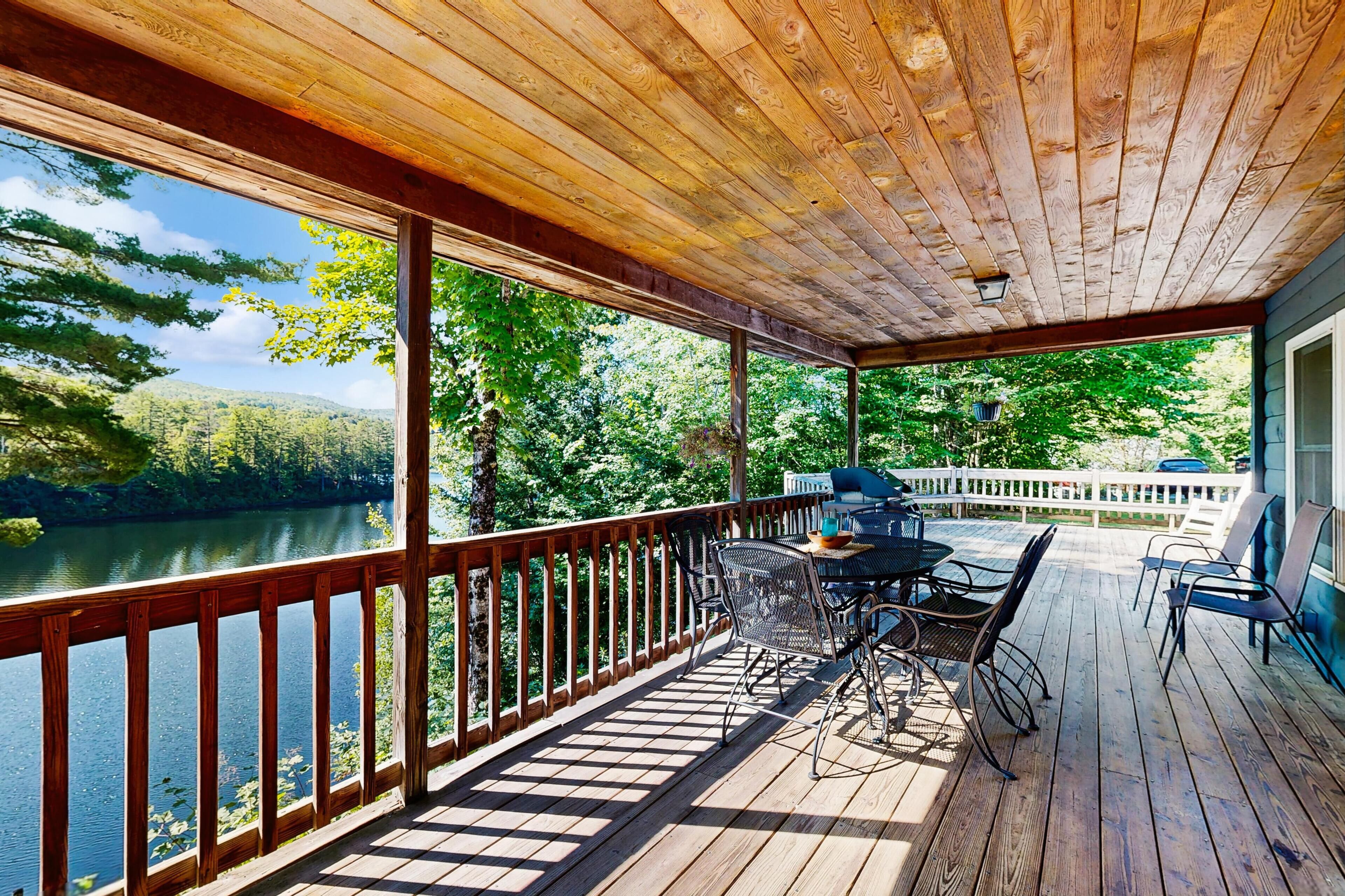 A wooden deck with a view of a lake and forest.