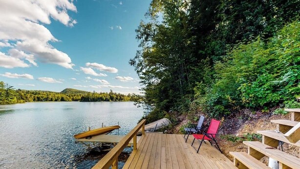 Une terrasse en bois offrant une vue sur un lac et une forêt.