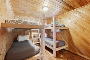 Une cabane en bois avec des lits superposés, une échelle et une fenêtre.