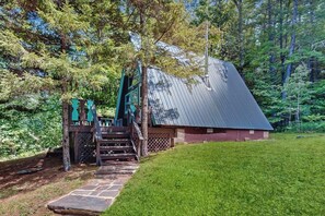 Eine rustikale Holzhütte mit Metalldach, umgeben von einem üppigen Grünwald.