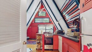 Una cocina con gabinetes rojos, una estufa y un lavamanos.