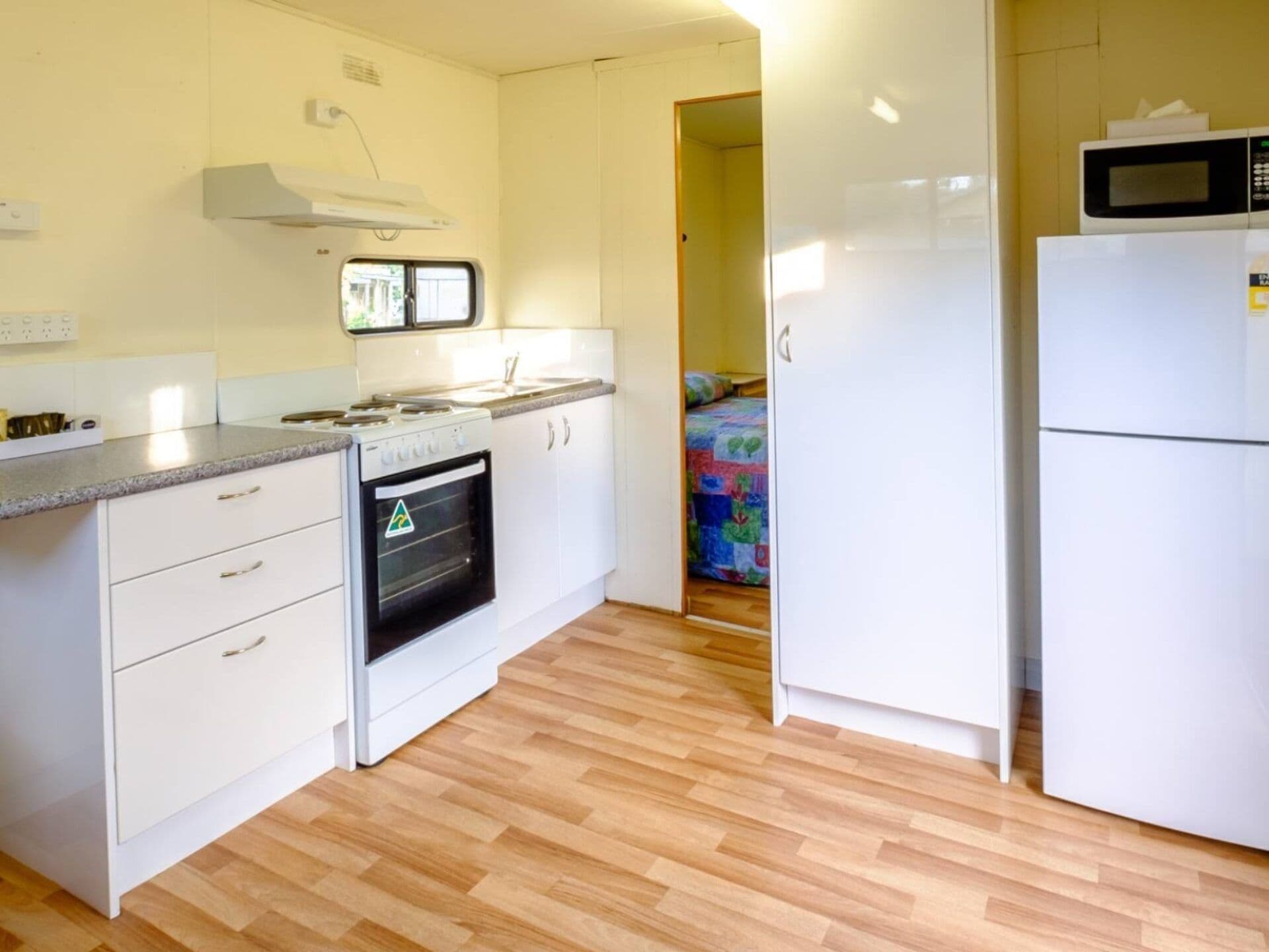 A compact kitchen with a stove, oven, microwave, and refrigerator.