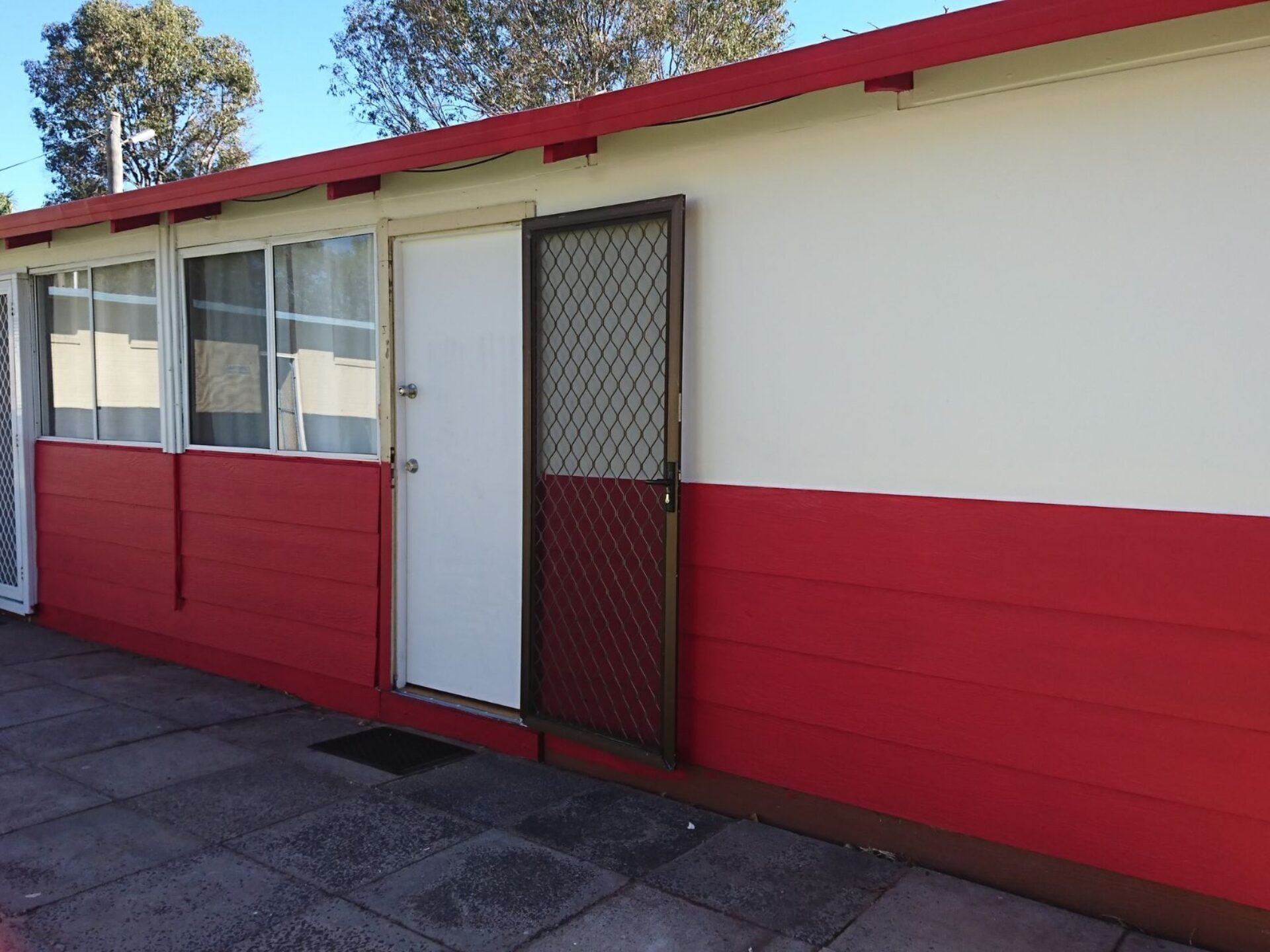 A red and white building with a closed door and windows.