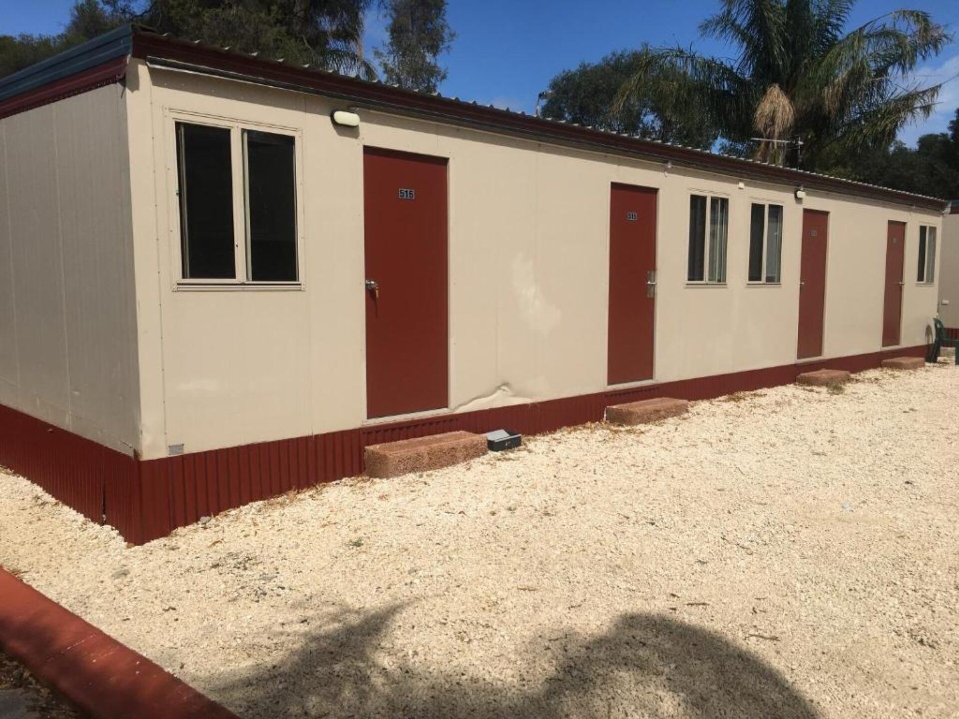 Il s’agit d’un bâtiment d’un seul étage, à l’extérieur beige et aux bordures rouges. Il possède une grande fenêtre sur le côté gauche et plusieurs portes aux encadrements rouges. Le sol est recouvert de gravier.
