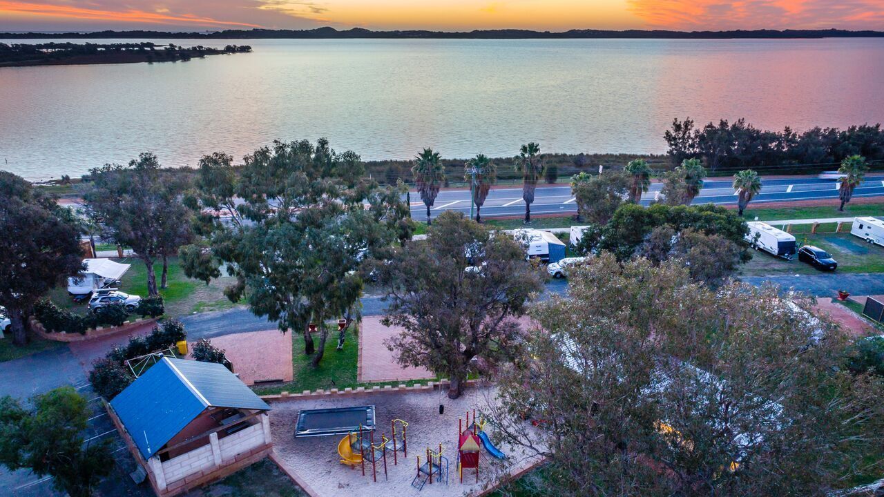 A campground with RVs, a playground, and a view of a large body of water.