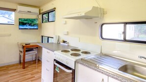 A compact kitchenette with a stove, oven, sink, and a small dining table.