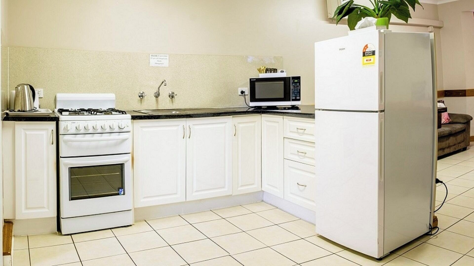 Una cocina con armarios blancos, estufa, microondas y refrigerador.