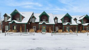 A row of wooden cabins with green trim and snow-covered roofs, set in a snowy landscape. - Spacious townhouse w/ gas fireplace, balcony, game room,  w/d,  loft (Dover)