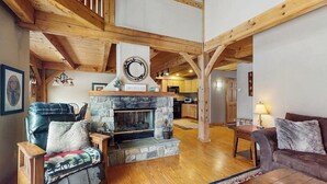 A cozy living room with a stone fireplace, wooden beams, a sofa, and a coffee table. - Spacious townhouse w/ gas fireplace, balcony, game room,  w/d,  loft (Dover)