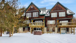 A two-story wooden house with a balcony on the first floor and a hot tub in the driveway. - Spacious townhouse w/ gas fireplace, balcony, game room,  w/d,  loft (Dover)