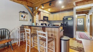 A kitchen with wooden cabinets, a black refrigerator, and a bar area with white chairs. - Spacious townhouse w/ gas fireplace, balcony, game room,  w/d,  loft (Dover)