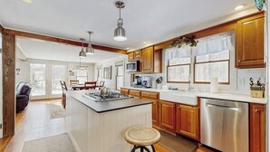 A modern kitchen with wooden cabinets, a central island, stainless steel appliances, and pendant lighting. - Cozy farmhouse w/ mountain views, woodstove, bbq, cable, close to Okemo, w/d (Cavendish)