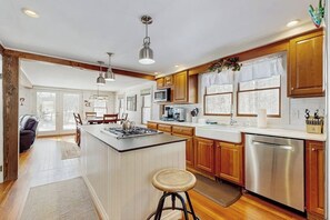 A modern kitchen with wooden cabinets, a central island, stainless steel appliances, and pendant lighting. - Cozy farmhouse w/ mountain views, woodstove, bbq, cable, close to Okemo, w/d (Cavendish)