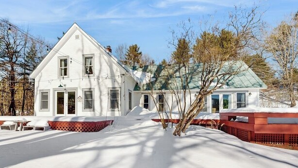 A white house with a green roof, surrounded by snow-covered ground and bare trees. - Cozy farmhouse w/ mountain views, woodstove, bbq, cable, close to Okemo, w/d (Cavendish)