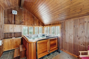 Ein Holzblock-Interieur mit Whirlpool, Holzschränken und großen Fenstern.