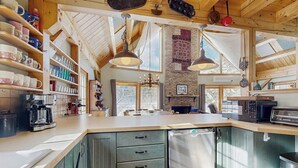 A kitchen with wooden cabinets, a refrigerator, a coffee maker, and hanging lights. - Lakefront house w/ mountain views, waterfront, gameroom, gym, a/c, w/d (Ludlow)