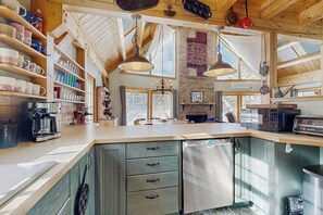 Eine Küche mit Holzausstattung, einem Kühlschrank, einer Kaffeemaschine und Pendelleuchten.