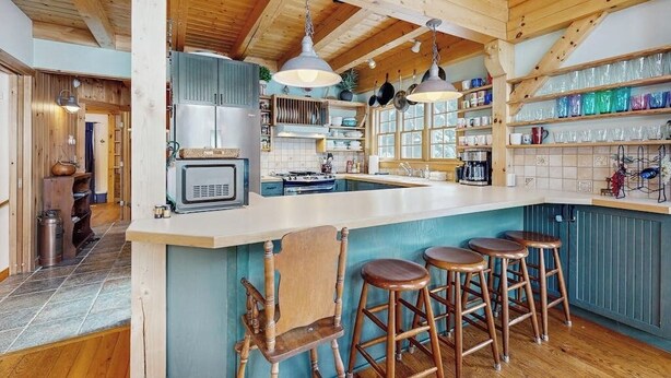 A kitchen with wooden beams, a large island with stools, and a microwave. - Lakefront house w/ mountain views, waterfront, gameroom, gym, a/c, w/d (Ludlow)