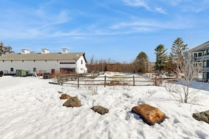 Schneebedeckte Landschaft mit einem weißen Gebäude, einem Holzzaun und mehreren Bäumen.