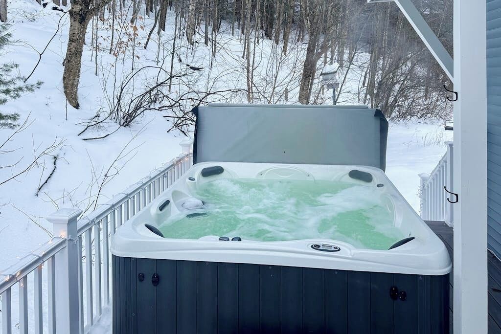 Un bain à remous sur une véranda, avec un paysage enneigé en arrière-plan.
