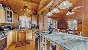 L’intérieur d’un chalet en bois comprend une cuisine, un coin repas et un ventilateur de plafond.