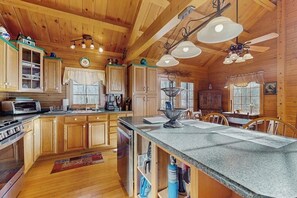Innenansicht einer Holzhütte mit Küche, Essbereich und Deckenventilator.