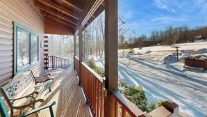 Une cabane en bois avec un porche, un banc et une vue sur un paysage enneigé.