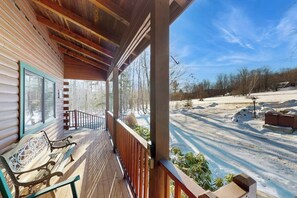 Eine Holzhütte mit Veranda, einer Bank und Blick auf eine verschneite Landschaft.