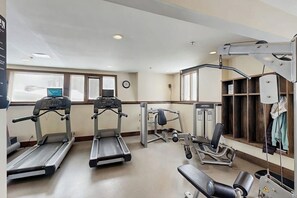 Ein Fitnessstudio mit Laufbändern, Kraftgeräten und einer Bank.
