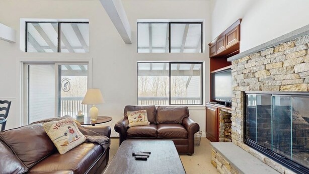 Una sala de estar con sof ás de cuero, chimenea y ventanas grandes.