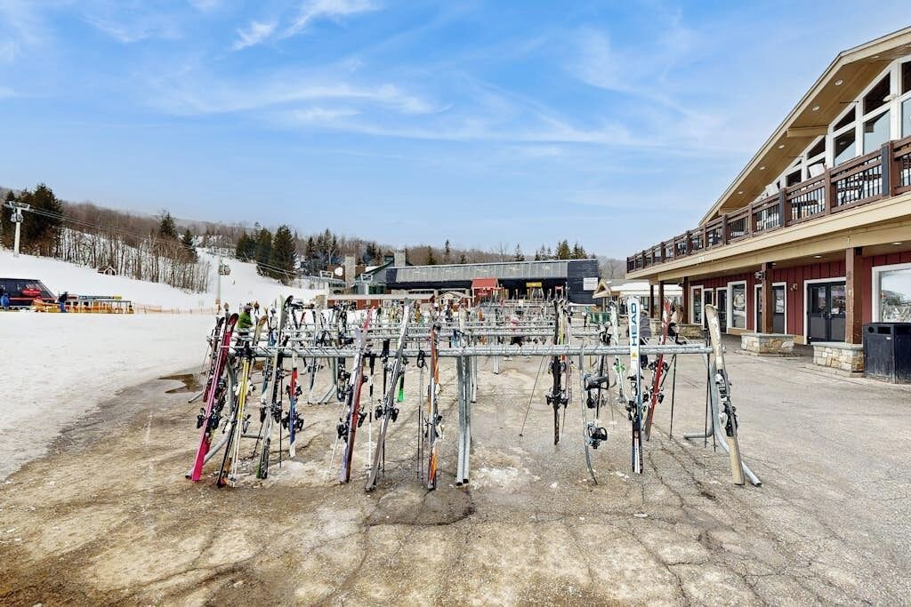 A ski resort with a ski lift, a building with a balcony, and a snow-covered ground.