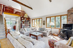 A spacious living room with a large sectional sofa, a fireplace, and a bookshelf filled with books.