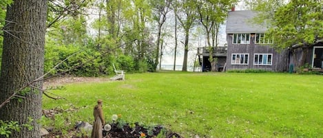 A house with a deck, a grassy yard, and a statue.