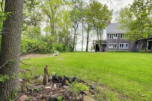 A house with a deck, a grassy yard, and a statue.