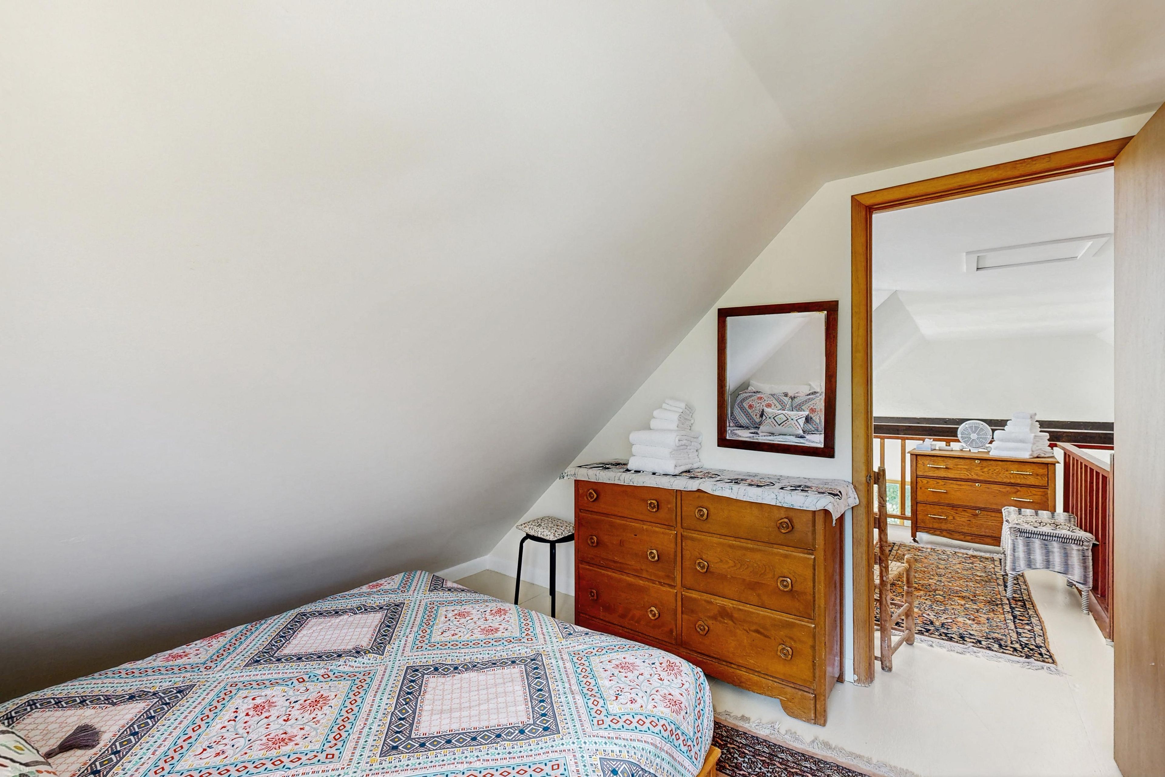 Une chambre à coucher avec un lit, une commode, un miroir et une petite table.